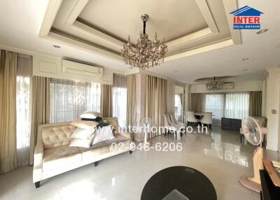 Spacious living room with a chandelier, sofa, and dining area