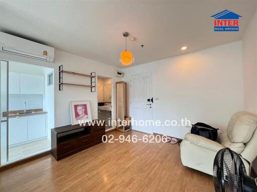 Spacious living room with hardwood floors, a white armchair, and modern lighting fixture