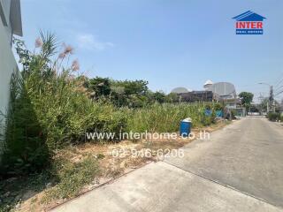 Empty residential plot with nearby sidewalk and street