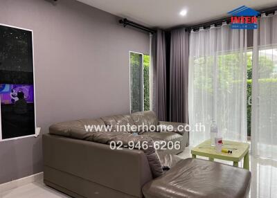 Living room with a sofa, window curtains, a small table, and contact information