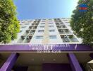 Facade of a multi-story residential building with balconies and trees