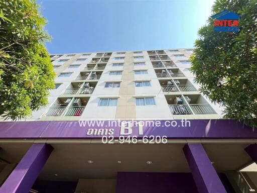 Facade of a multi-story residential building with balconies and trees