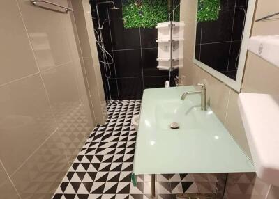 Modern bathroom with geometric floor tiles and a glass sink