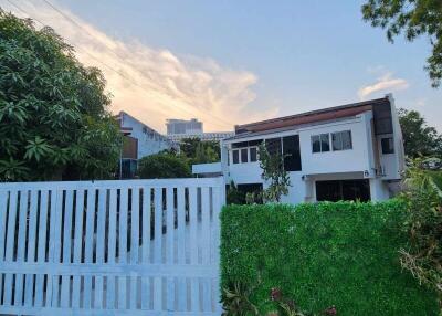 Modern two-story house exterior with gate and greenery