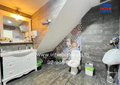 Well-lit bathroom with a vanity, toilet, urinal, and unique tiled design.
