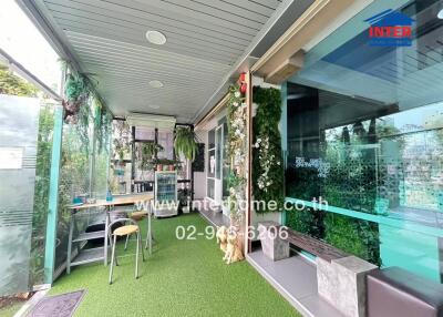 Outdoor patio area with green synthetic grass, bar table, and glass walls
