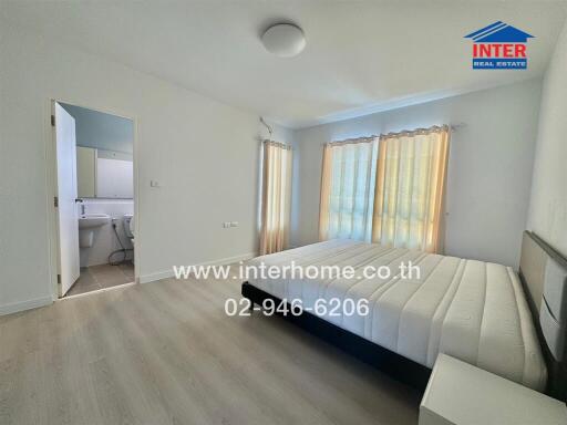 Spacious bedroom with natural light, adjoining en-suite bathroom.