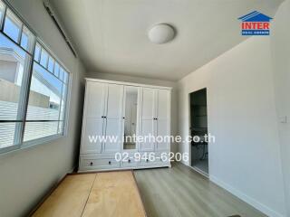 Bedroom with a large white wardrobe and wooden bed frame