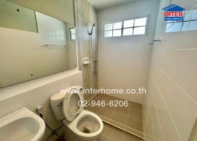 Bathroom with toilet, sink, shower area, and tiled walls