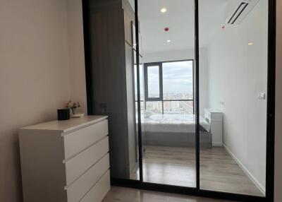 Modern bedroom with city view, wooden flooring, and reflective glass wardrobe
