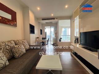 Modern living room with a sofa, coffee table, dining area, and large window with city view.