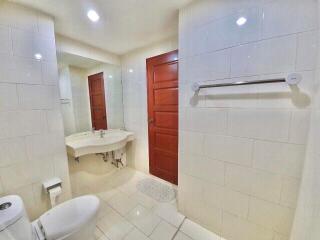 Modern bathroom with tiled walls, red wooden door, and mirror.