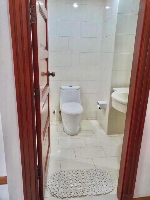Small bathroom with toilet, sink, and tiled walls