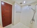 Modern bathroom with white tiles, wooden door, and shower area