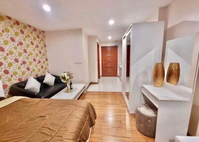 Bedroom with floral wallpaper, bed, sofa, dressing table, and wooden floor