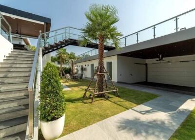 Modern outdoor area with stairs, glass railings, greenery, and a garage