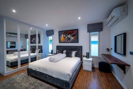 Modern bedroom with bed, mirrored closets, and artwork