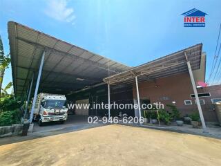 Exterior view of a commercial warehouse with a large truck parked under a covered area