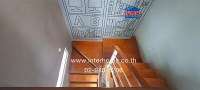 Interior view of a wooden staircase with artistic ceiling design