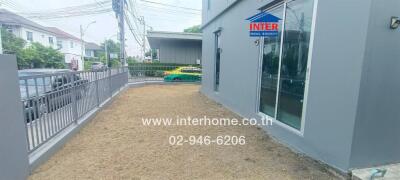 Side yard view of a property with grass and grey exterior walls