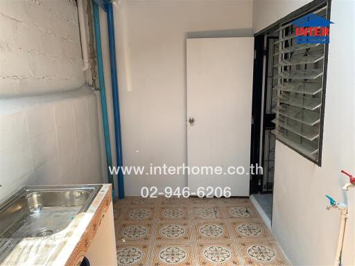 Small kitchen area with sink, wall tile, and a door