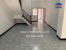 Spacious living room with tile flooring, stairs leading to the upper floor, and an open entryway.