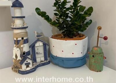 Decorative items on a shelf including a small lighthouse model, a potted plant, and other ornaments