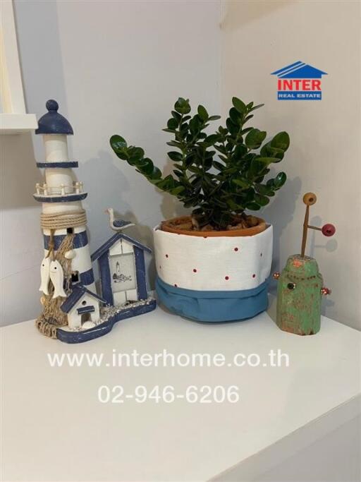 Decorative items on a shelf including a small lighthouse model, a potted plant, and other ornaments