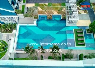 Aerial view of a spacious outdoor swimming pool area with surrounding greenery and lounging area.