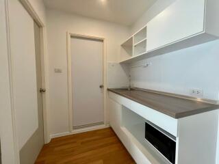 Compact modern kitchen with white cabinets and wooden flooring