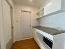 Compact modern kitchen with white cabinets and wooden flooring