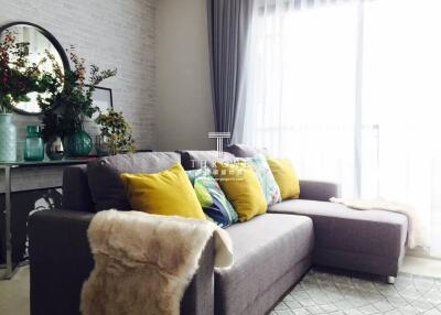 Modern living room with sectional sofa, decorative pillows, and a console table with accessories
