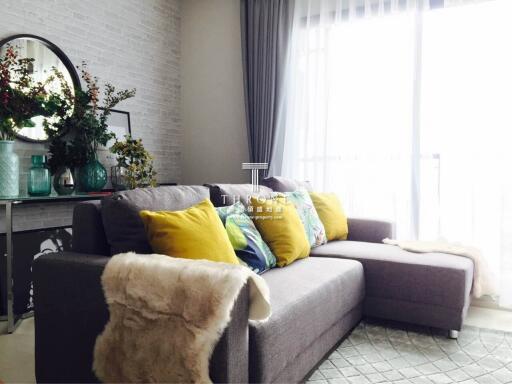 Modern living room with sectional sofa, decorative pillows, and a console table with accessories