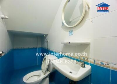 Bathroom with blue and white tiles, featuring a toilet and a sink with a mirror