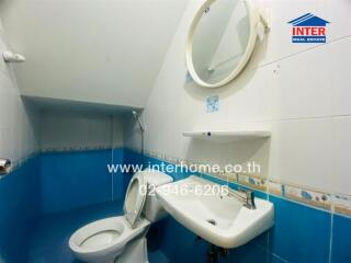 Bathroom with blue and white tiles, featuring a toilet and a sink with a mirror