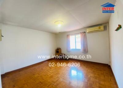 Empty bedroom with wooden flooring, air conditioning unit, and window with pink curtains