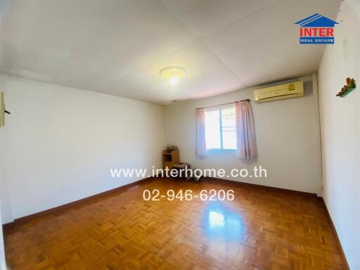 Empty bedroom with wooden flooring, air conditioning unit, and window with pink curtains