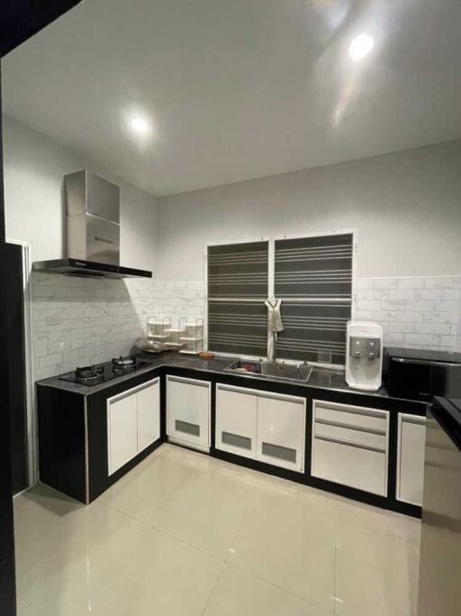 Modern kitchen with white and black cabinetry, stainless steel appliances, and tiled backsplash