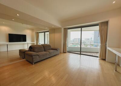 Spacious living room with city view, mirrored wall, and wooden flooring