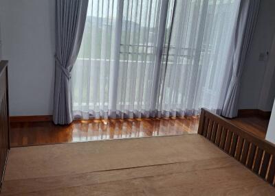 Spacious bedroom with large windows, wooden flooring, and air conditioning
