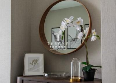 A stylish corner of the living room with a round mirror, potted orchid, and framed wall art.