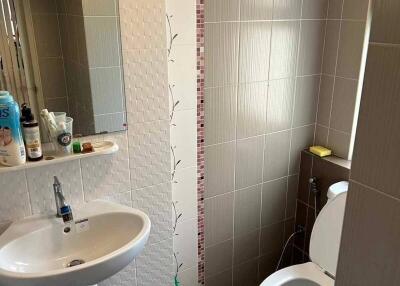Modern bathroom with tiled walls, sink and toilet