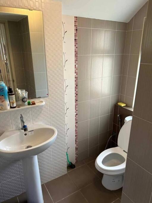 Modern bathroom with tiled walls, sink and toilet