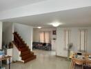 Spacious living room with staircase, windows, and seating area