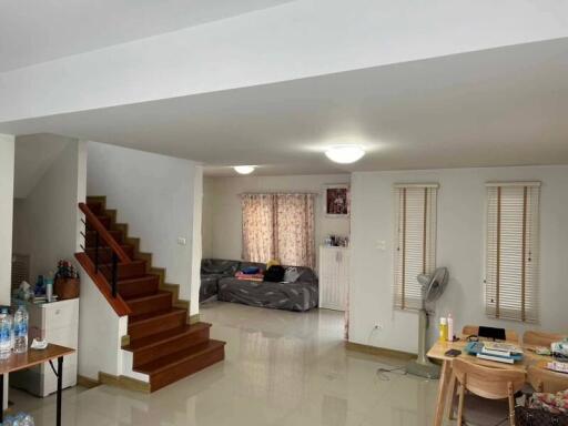 Spacious living room with staircase, windows, and seating area