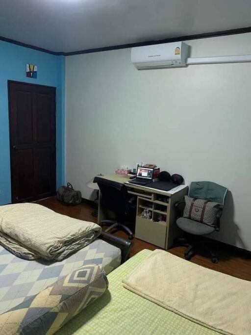 A bedroom with twin beds, a desk, and an air conditioning unit