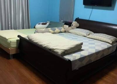 Bedroom with wooden floor, two beds, and a wall-mounted TV