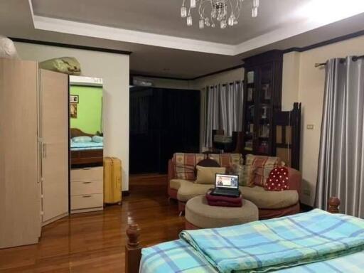 Spacious bedroom with elegant wooden flooring, a cozy sitting area, wardrobe, and study desk