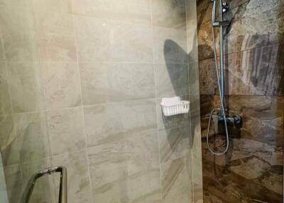 Modern shower area with wall-mounted showerhead and brown tile accents