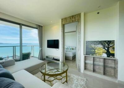 Bright living room with ocean view, modern furnishings, and wall-mounted TV